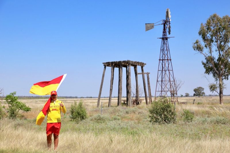 Lifesaver holding a flag in front of a windmill