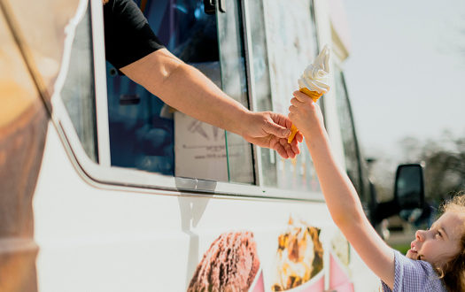 An exciting little girl has just gotten a treat from an ice cream van.